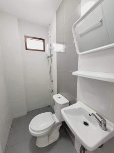 a white bathroom with a toilet and a sink at Mara's holiday house in Pattaya South