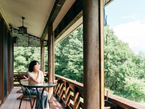 Eine Frau, die an einem Tisch auf einer Veranda sitzt. in der Unterkunft 津川温泉 清川高原保養センター in Aga