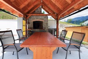 une table et des chaises en bois sur une terrasse avec une cheminée dans l'établissement Holiday house with a parking space Kuzelj, Gorski kotar - 20489, à Delnice