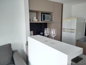 dos copas de vino sentadas en un mostrador blanco en una cocina en Hermoso departamento zona Guemes en Mar del Plata