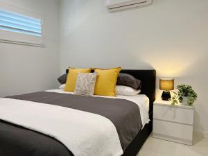 a bedroom with a large bed with yellow pillows at One on Harris Apartments in Wellington Point