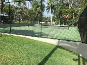 a tennis court with a fence and grass at Brisbane Gateway Resort in Rochedale