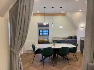 a dining room with a table and green chairs at La Chaumière Luxury Domain with 2 Apartments Spa and Pool near Disneyland in Coupvray