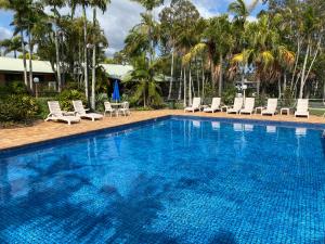 einen großen Pool mit Stühlen und Palmen in der Unterkunft Brisbane Gateway Resort in Rochedale