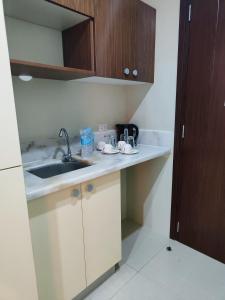 una pequeña cocina con fregadero y armarios de madera. en G Square Residences en Manila