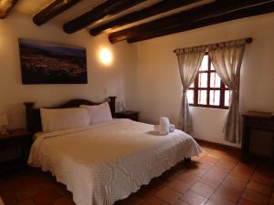 1 dormitorio con cama blanca y ventana en HOTEL AQUA VITAE, en Villa de Leyva