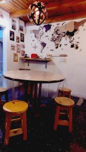 a table with two stools and a map on the wall at Hostel Piltri in El Bolsón