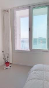 a bedroom with a bed and two large windows at Tongyeong Canal Ocean View in Tongyeong