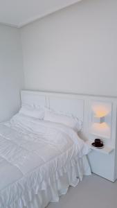 a white bed with white sheets and a nightstand with a lamp at Tongyeong Canal Ocean View in Tongyeong