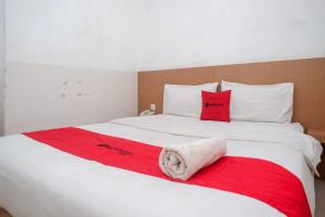 1 dormitorio con 1 cama blanca grande con almohadas rojas en RedDoorz @ Pengayoman Panakkukang 2, en Makassar
