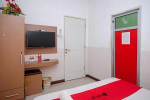 1 dormitorio con puerta roja y TV en RedDoorz @ Pengayoman Panakkukang 2, en Makassar