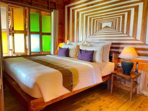 a bedroom with a large bed with purple pillows at Phi Phi Phu Chalet Resort in Phi Phi Don