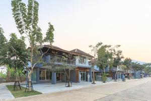 a building on the side of a street with trees at Happy Land Residence in Ban Nam Cham