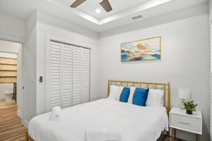 Dormitorio blanco con cama con almohadas azules en Chic and cozy private getaway! en Tampa