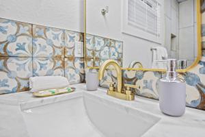 a bathroom with a sink and a gold faucet at Chic and cozy private getaway! in Tampa
