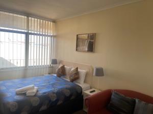 a small bedroom with a bed and a couch at Grand Central Motel in Mount Gambier