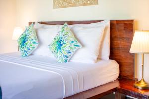 a bed with blue and white pillows on it at Cadlao Resort and Restaurant in El Nido