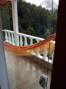 a hammock on a balcony with a view of trees at Bangalô - Sítio Cachoeiras do Caledônia in Nova Friburgo