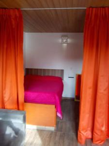 a bedroom with a red bed and orange curtains at Bangalô - Sítio Cachoeiras do Caledônia in Nova Friburgo