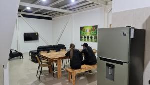two people sitting at a table in a room with a refrigerator at Finca Pradera Real in Circasia
