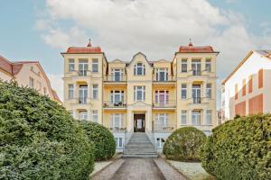 班辛海的住宿－Villa Meereswoge - Goldstern，前方设有楼梯的大型黄色建筑