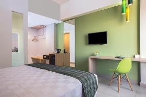 a bedroom with a bed and a desk and a tv at KHAS Makassar Hotel in Makassar