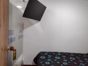 a room with a bed and a tv on the wall at HOTEL DANUBIO in Bogotá
