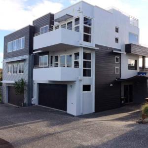 a large white building with a garage at Luxury Beach Guest House in Papamoa
