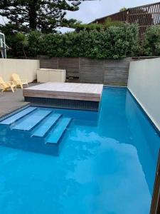 a swimming pool with blue water in a backyard at Luxury Beach Guest House in Papamoa