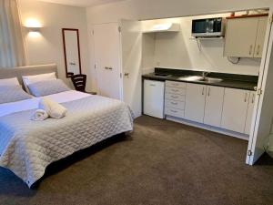 een kleine slaapkamer met een bed en een keuken bij Luxury Beach Guest House in Papamoa