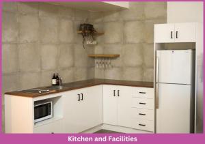 a kitchen with white cabinets and a refrigerator and refridgerator at Strand Park Unit - U1 Ground floor in Townsville