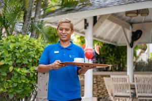 Een man met een bord met een wijnglas erop. bij Lembongan Island Beach Villas in Nusa Lembongan