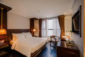 Dormitorio con cama, escritorio y TV en Le Jardin Hotel Haute Couture en Hanói