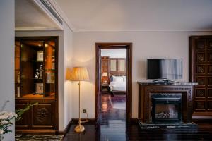 a living room with a fireplace and a television at Le Jardin Hotel Haute Couture in Hanoi