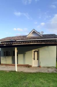 une maison blanche avec une porte blanche et de l'herbe dans l'établissement Casa pedrinhas, à Ilha Comprida