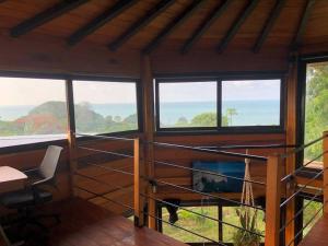 Habitación con ventanas, escritorio y mesa. en Casa de madera con HYDROMASAJE vista al mar, en Atacames