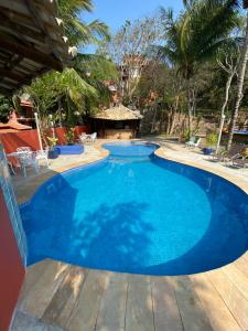 a large blue swimming pool with a wooden deck at Hotel Cave do Sol in São Pedro da Aldeia