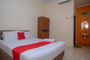 una camera da letto con un letto con una coperta rossa sopra di RedDoorz near Jalan Wolter Monginsidi Manado a Manado
