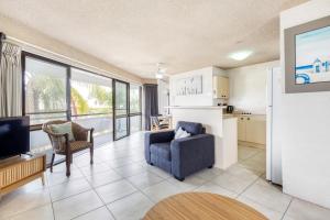 a living room with a couch a chair and a tv at Tindarra Apartments in Alexandra Headland