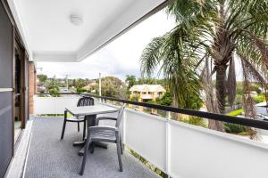 balcón con mesa, sillas y palmeras en Tindarra Apartments, en Alexandra Headland