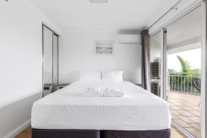a bedroom with a white bed and a balcony at ALEXANDRA BEACH RESORT-ALEX412 in Alexandra Headland
