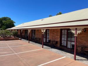 ein Gebäude mit Markise und Tischen und Stühlen davor in der Unterkunft Philadelphia Motor Inn in Echuca