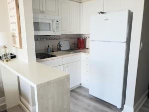 a kitchen with white cabinets and a white refrigerator at Beautiful one bedroom oceanfront condo in Daytona Beach
