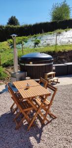 La Rivière Saint Sauveur的住宿－La cressonnière maison vue sur étang avec bain finlandais，热水浴池旁的野餐桌和椅子