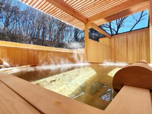 a hot tub in a wooden house with a waterfall at Kose Onsen in Karuizawa