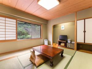 a living room with a wooden table and a tv at Shin Kabakawa Kanko Hotel in Takamatsu