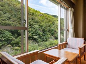 Zimmer mit einem Tisch und Stühlen sowie einem großen Fenster in der Unterkunft Shin Kabakawa Kanko Hotel in Takamatsu