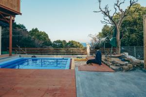 a person sitting on a deck next to a swimming pool at Diamond・Yu　Atami in Ajiro