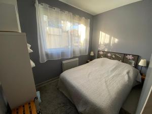 Un dormitorio con una cama blanca y una ventana. en Appartement en rez-de-jardin à 100m de la plage avec terrasse et parking - FR-1-413-107, en Capbreton