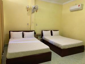 two beds in a small room with a fan at HeangKanha GuestHouse in Phumĭ Chŏng Kaôh